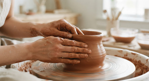Hands working with terracotta clay on a potter's wheel